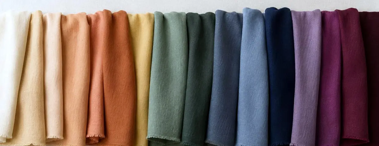 Fila de paños de tela ordenados de los tonos cálidos a los fríos: crema, durazno, terracota, oliva, verde, celeste, azul, violeta y borgoña.